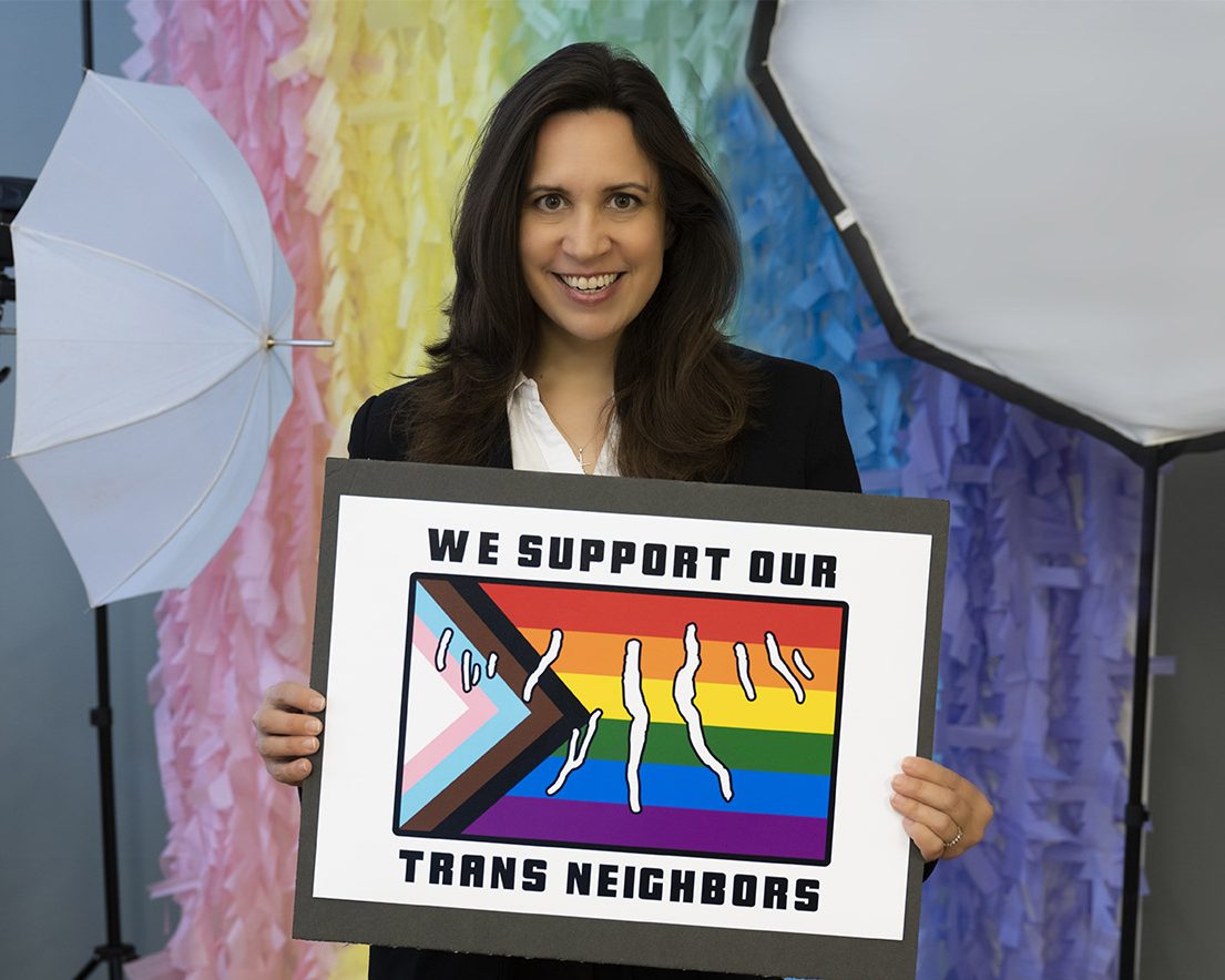Picture of woman holding Committing to the Trans Campaign sign