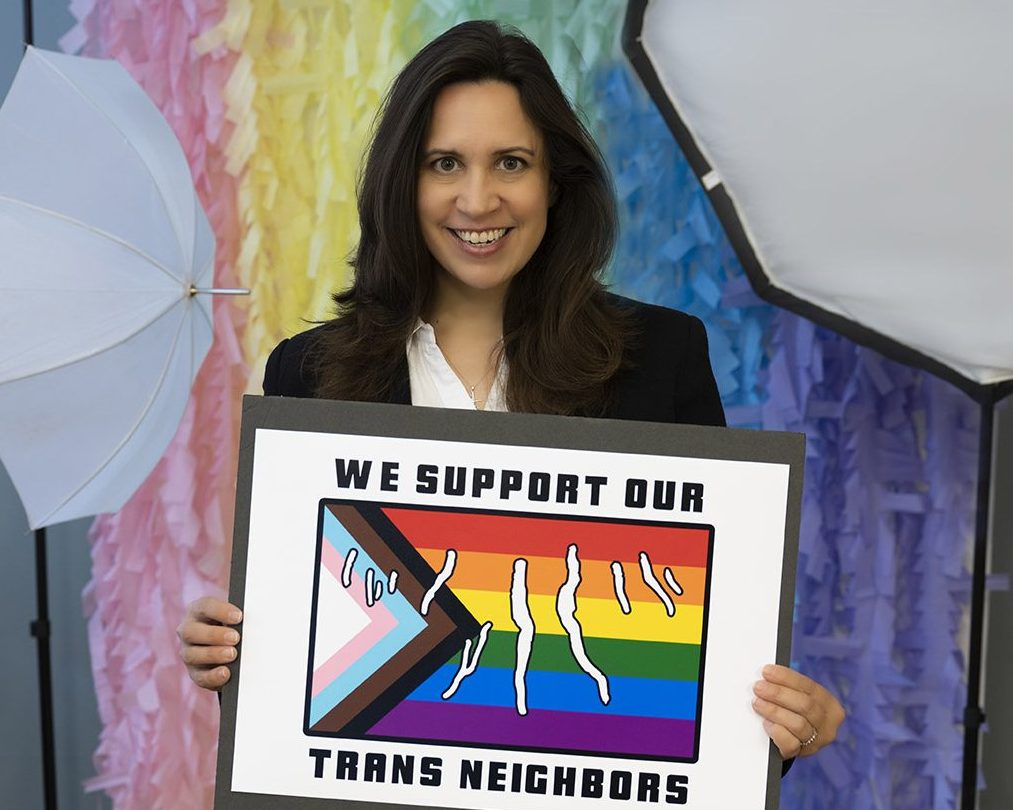 Picture of woman holding Committing to the Trans Campaign sign